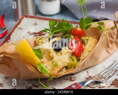 tasty white fish fillet baked in parchment with vegetables and cheese Stock Photo