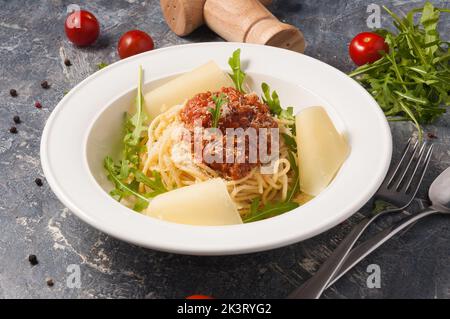 tasty spaghetti Bolognese on a white plate with Parmesan and arugula. Horizontal frame Stock Photo