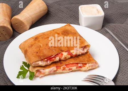 tasty pancakes with ham, cheese and tomatoes on a white plate. horizontal frame Stock Photo