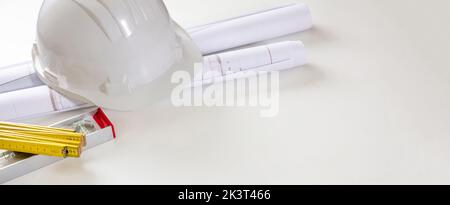 Construction project, real estate. Architect engineer safety helmet and building blueprint plans on white, copy space, banner Stock Photo