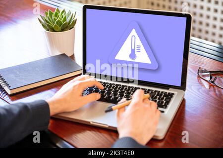 High temperature warning sign on a laptop screen.  Computer overheating concept. Heavy load and hot weather danger. Business office desk background. Stock Photo