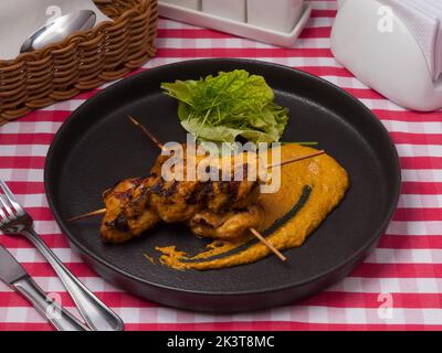 tasty chicken skewers with curry on a black plate Stock Photo
