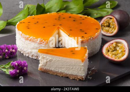 Tender cheese mass on a crispy base with a sweet mango-passion fruit coolie filling. Decorated with passion fruit seeds on top Stock Photo