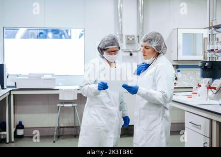 Young women standing with papers in laboratory. Stock Photo