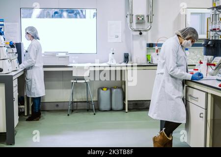 Side view of young biologists doing experiment in lab. Stock Photo