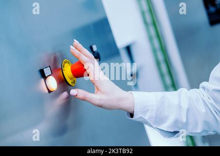 Close up crop view of hand of anonymous researcher pushing stop emergency button Stock Photo