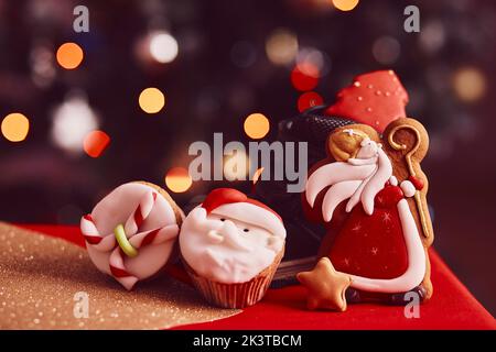 Boots filled of treats. Saint Nicholas cookies and cupcakes on bokeh background. Traditional holiday in Europe. Copy space Stock Photo