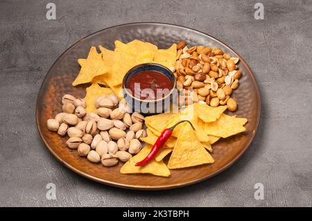 tasty beer snacks: nachos with salsa sauce, pistachios, peanuts Stock Photo