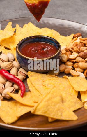 tasty beer snacks: nachos with salsa sauce, pistachios, peanuts. close-up Stock Photo