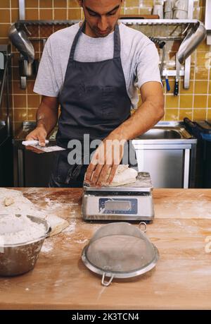 baker weighing bread dough on scale at bakery Stock Photo - Alamy