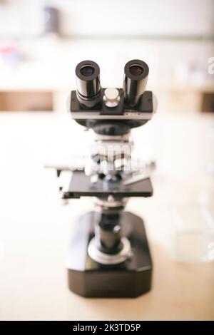 full view of microscope on a desk against a blurred background Stock Photo
