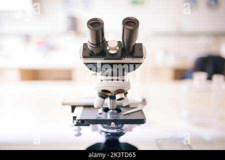 full view of microscope on a desk against a blurred background Stock Photo