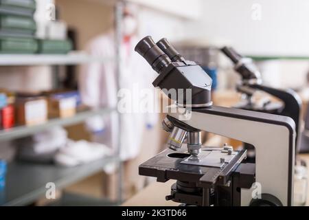 full view of microscope on a desk against a blurred background Stock Photo
