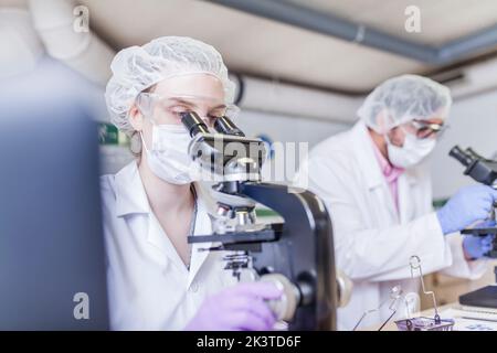 woman and man scientists looking through microscope at laboratory Stock Photo