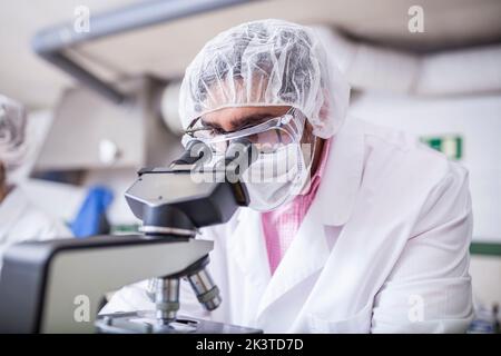 Man scientist looking through microscope at laboratory Stock Photo