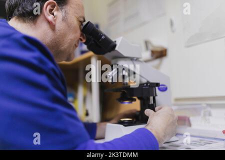 Side view of doctor looking through microscope in laboratory Stock Photo