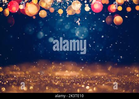 Festive golden glittering in the dark night background with blurred bokeh lights and snow. Christmas and winter holidays background Stock Photo
