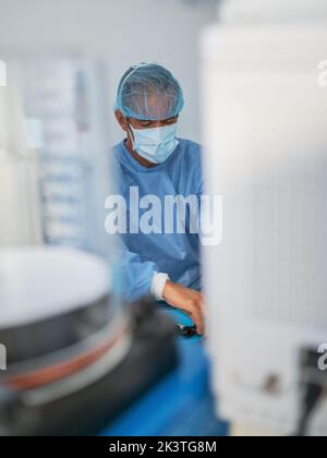 Mature man in medical uniform smiling and looking away while working in modern clinic Stock Photo