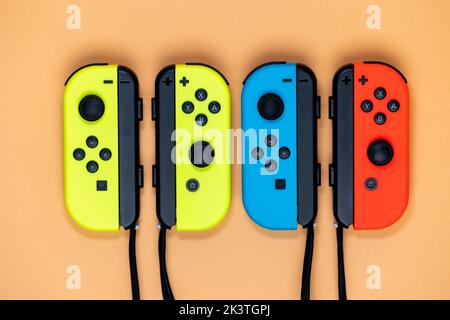 Nintendo Switch Joy-Cons aligned in a row. Yellow blue and red Joy-Cons top view with orange Background. Stock Photo