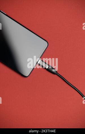 Phone with Micro USB to USB Type C Adapter plugged in. Phone USB Adapter. Phone top view with red background. Stock Photo