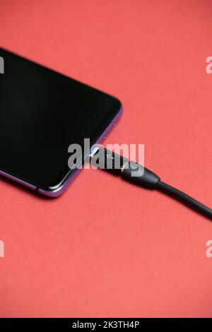 Phone with Micro USB to USB Type C Adapter plugged in. Phone USB Adapter. Phone top view with red background. Stock Photo