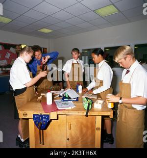 Teenagers Working in Woodwork Class Teacher Helping Student with Hand Drill England Stock Photo