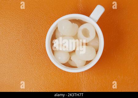 longans fruits in cup on orange background  Stock Photo