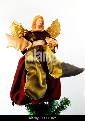 Fairy Wearing Red Velvet Dress with Gold Wings on top of the Christmas Tree Stock Photo