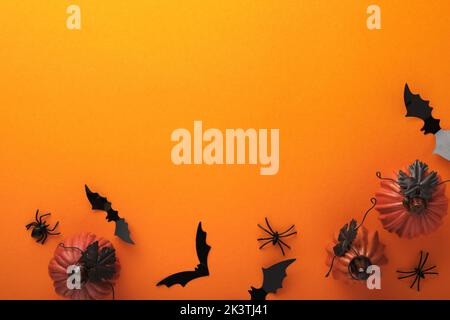 Halloween background. Flock of black bats, spider, pumpkin, skeleton and leaves for Halloween. Black paper bat silhouettes on orange background. Autum Stock Photo