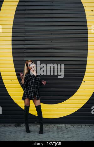 Happy young black woman on city street in front of a black wall Stock Photo
