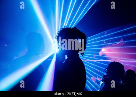 Happy black couple dancing against colorful neon illumination during party in nightclub Stock Photo