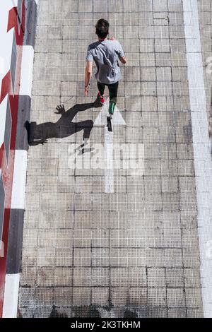 from above young guy with leg prosthesis running up paved slope against shabby building during workout on city street Stock Photo