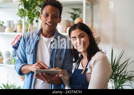 Plant nursery owners smiling at the camera while using digital tablet Stock Photo
