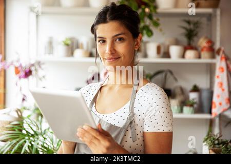 Young adult female nursery worker holding digital tablet Stock Photo