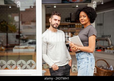 African American female bakery owner standing with colleague at doorway Stock Photo