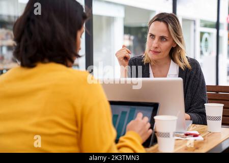 Mid-shot view of female co-workers discussing in outdoors office Stock Photo