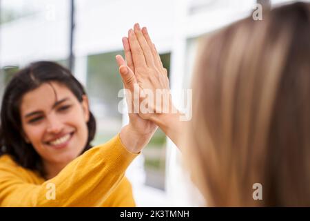 Shot of Latin-American businesswoman high-fiving her co-worker in outdoors office Stock Photo