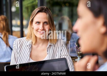 Front view of female entrepreneur working with her Latin-American partner seen out of focus from behind Stock Photo
