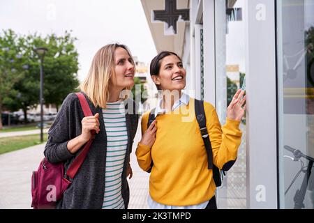 Photo of two female friends looking at shop windows and having a good time together Stock Photo