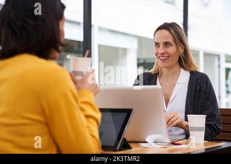 Medium shot of two female co-workers talking about business topics in outdoors office Stock Photo