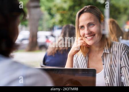 Mid-shot of two female co-workers having a good time while working in outdoors office Stock Photo
