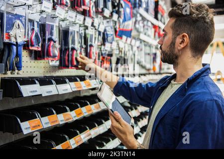 Male hardware shop worker setting prices on digital tablet Stock Photo