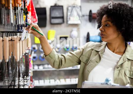 African American female hardware shop worker taking notes of products on clipboard Stock Photo