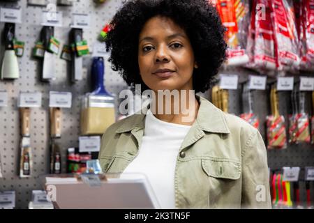African American female hardware shop owner looking at the camera while taking inventory Stock Photo