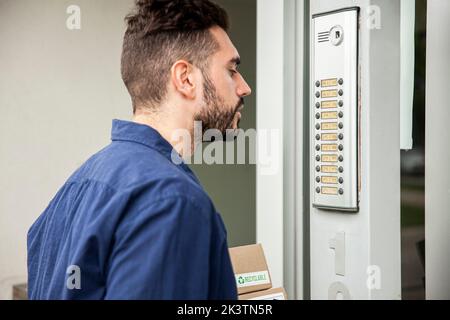Delivery man standing in doorway while waiting to be attended Stock Photo