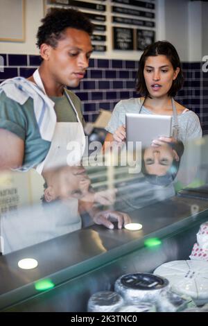 Grocery store coworkers discussing over digital tablet Stock Photo
