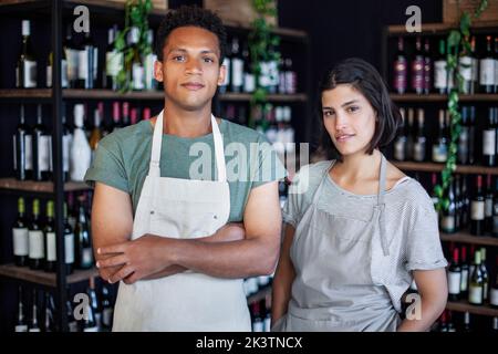Latin American liquor store owner standing next to partner while looking at the camera Stock Photo
