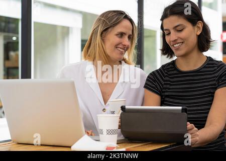 Medium-shot of two diverse female entrepreneurs working with laptop computer and digital tablet Stock Photo