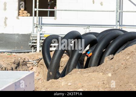 Black PVC flexible corrugated plastic insulation pipes tubing of electrical cables wire at undeground installation. New modern building construction Stock Photo
