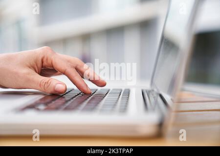 Close-up side view shot of woman's hand typing on a laptop computer Stock Photo